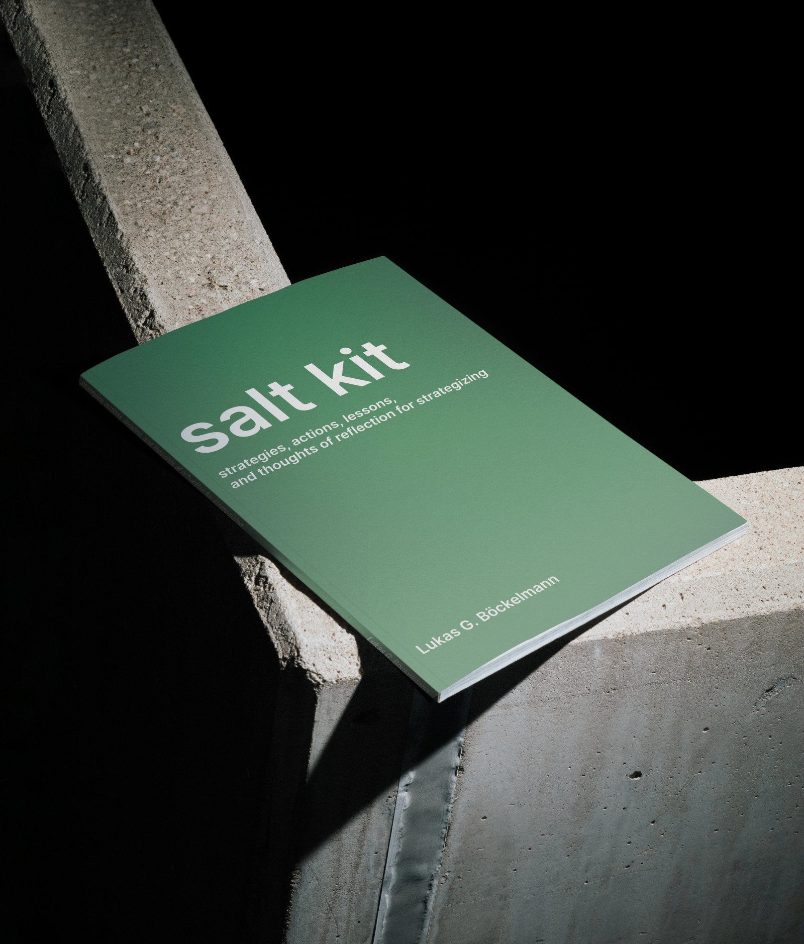 The salt kit print lying flat on a concrete rail- ing with high contrast lighting and dark shadows. The green cover shows the title as well as subtitle and names the author