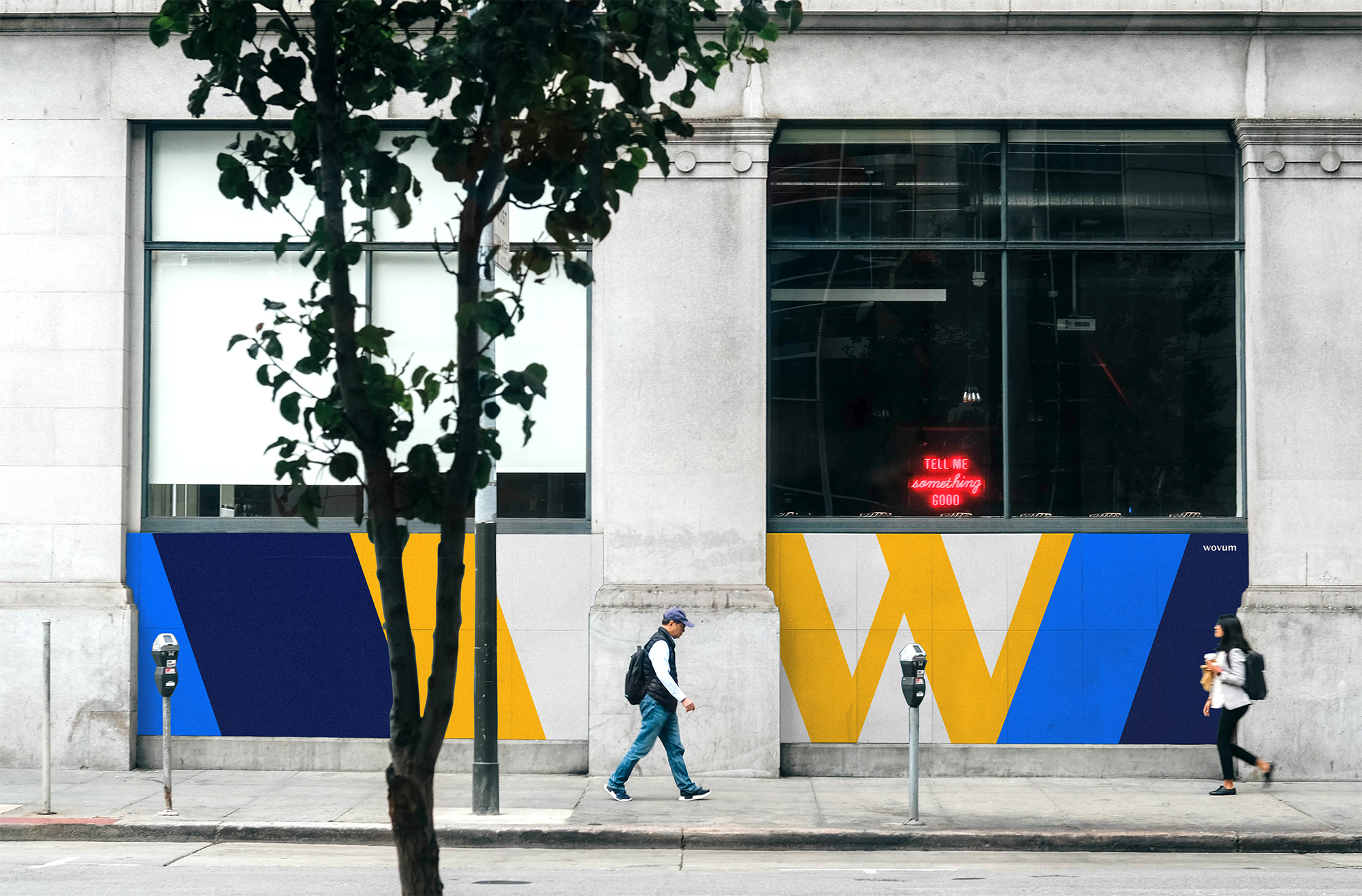 The image shows a photograph of wovum posters in an urban setting.